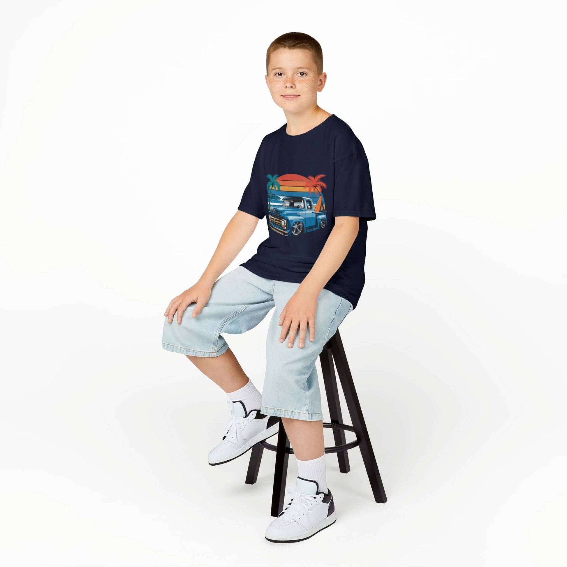 Boy sitting on a stool wearing a retro kids t-shirt with vintage pickup truck design, perfect for car lovers.
