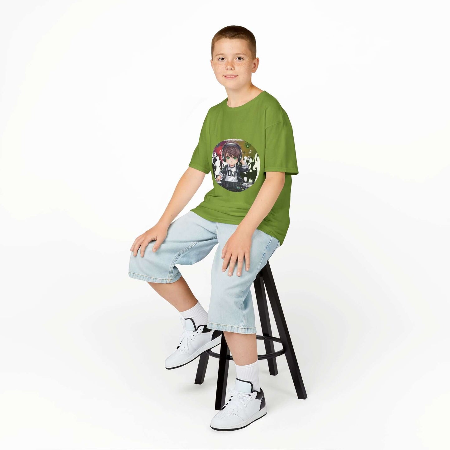 Boy sitting on a stool wearing a green DJ chibi boy party music lover t-shirt, paired with denim shorts and sneakers.
