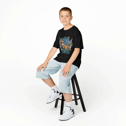 Boy sitting on a stool wearing a black kids tee with lazy cat at beach design and 'Too Lazy to be Lazy' text.