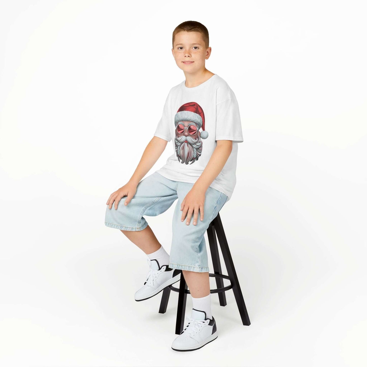 Kid wearing a modern Santa T-shirt with sunglasses, showcasing holiday cheer and festive vibes on a stool.