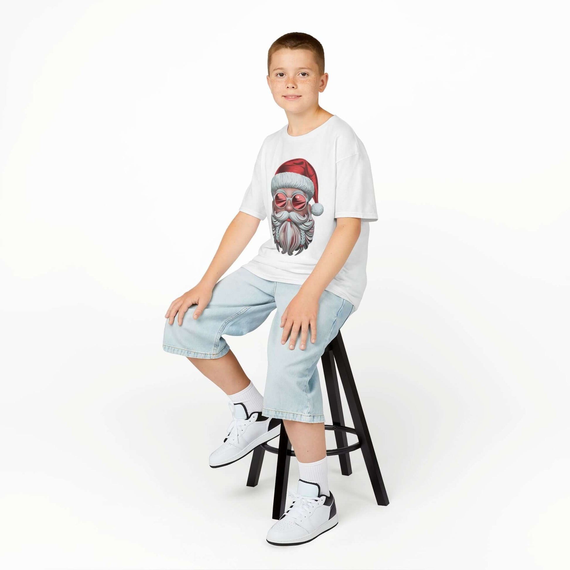Kid wearing a modern Santa T-shirt with sunglasses, showcasing holiday cheer and festive vibes on a stool.