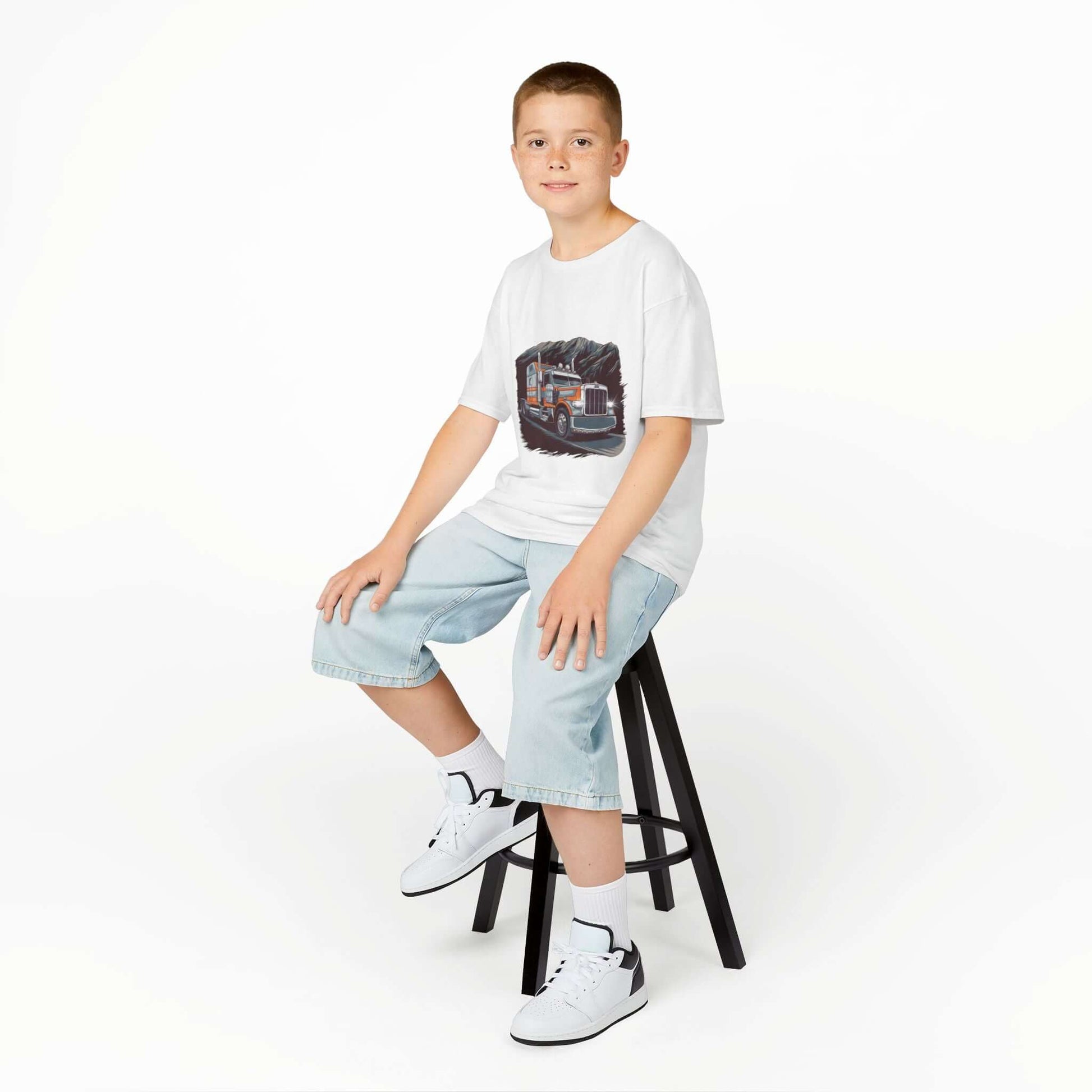 Boy sitting on a stool wearing a Kids Tee with a cool custom old truck design, perfect for truck lovers.