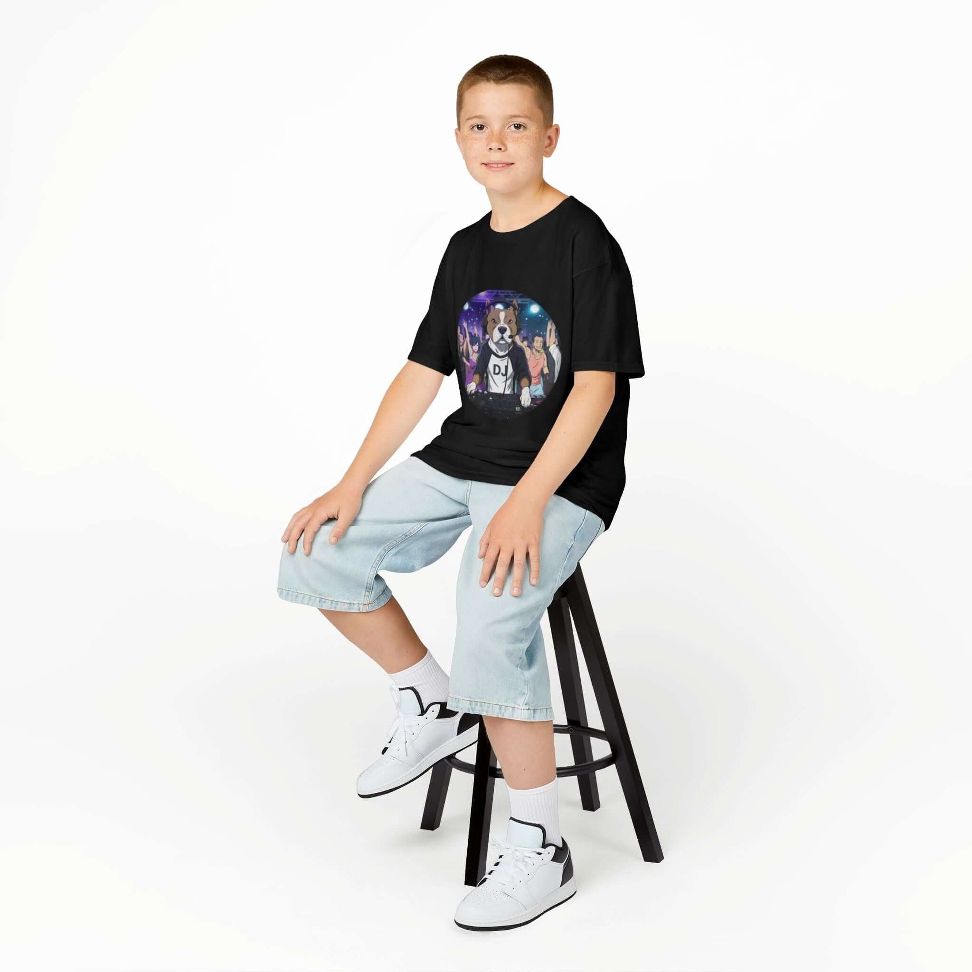 Boy sitting on a stool wearing a DJ Dog Kids Tee, showcasing a vibrant DJ dog design, perfect for music lovers.