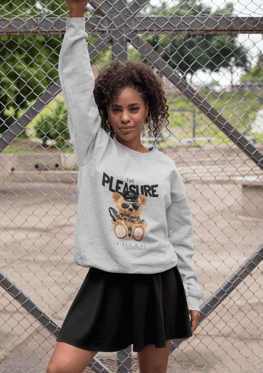 Woman wearing a playful Crewneck Sweatshirt featuring a teddy bear and the phrase "The PLEASURE is all mine."