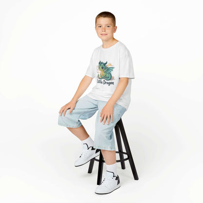 Boy wearing a 'Little Dragon' cartoon character Kids Tee, sitting on a stool, showcasing playful design.
