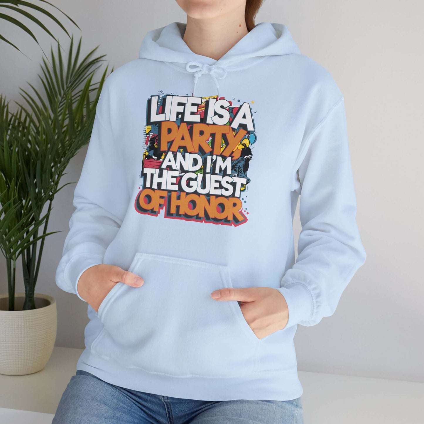 Hooded sweatshirt with funny quote 'Life is a party and I'm the guest of honor' against party scene background.