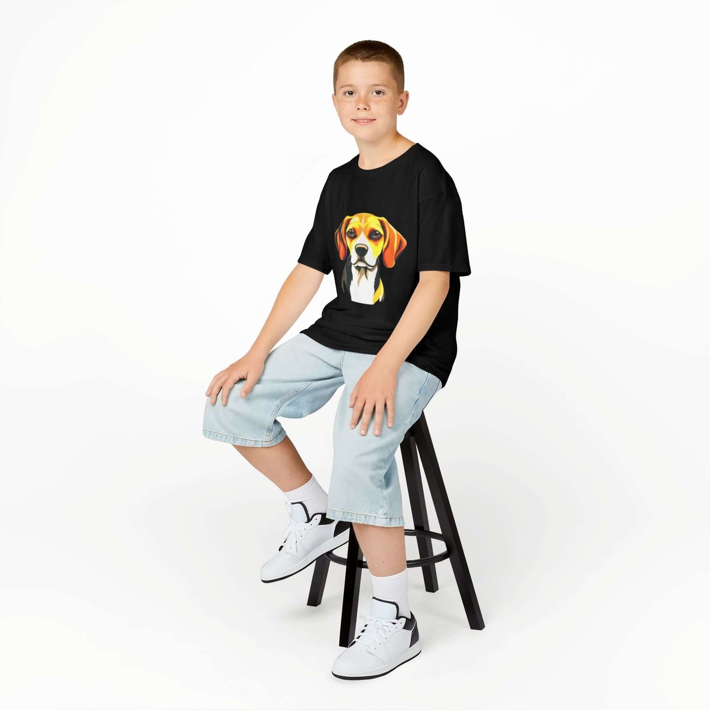 Boy sitting on a stool wearing a black kids tee with a cute hound dog design, perfect for young animal lovers.
