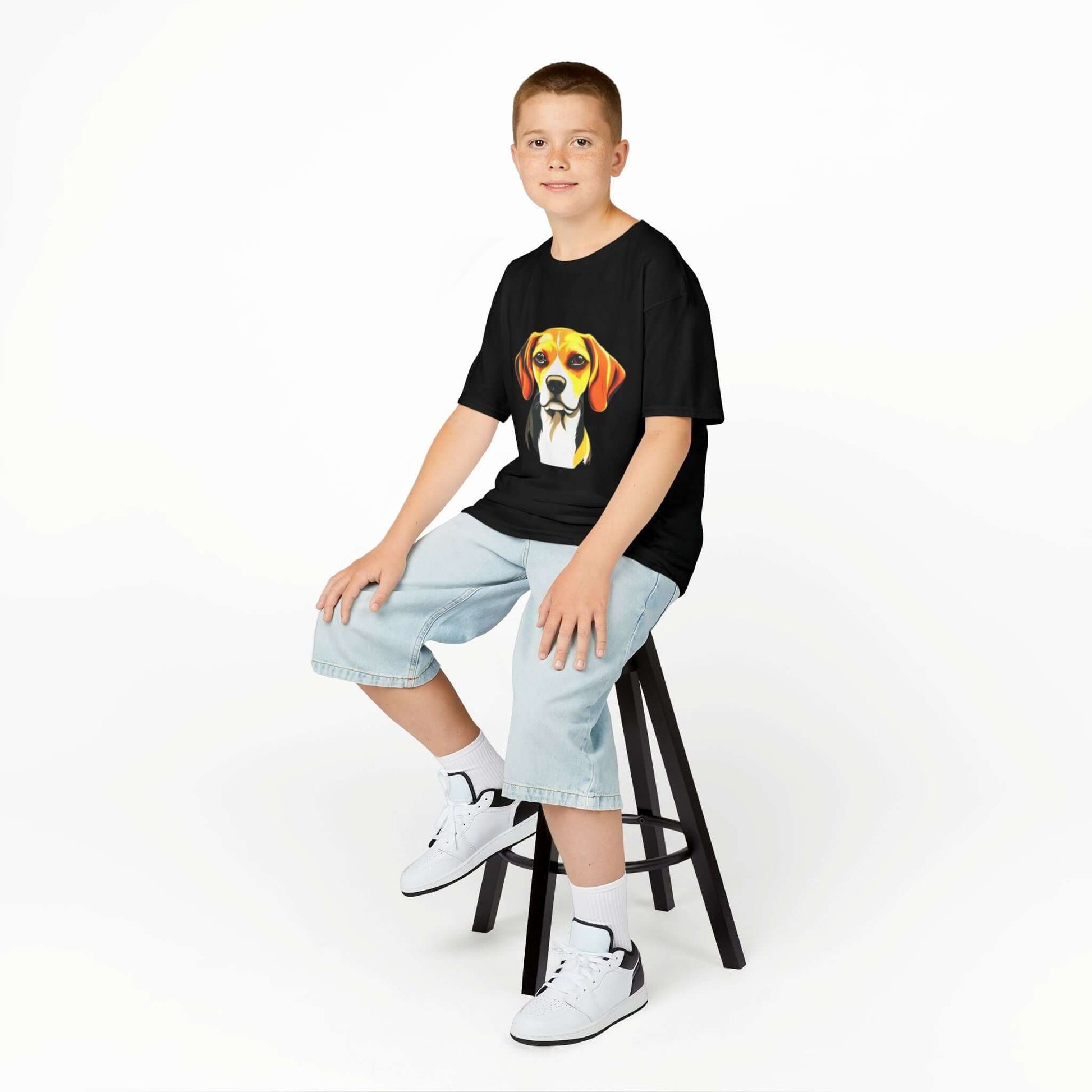 Boy sitting on a stool wearing a black kids tee with a cute hound dog design, perfect for young animal lovers.